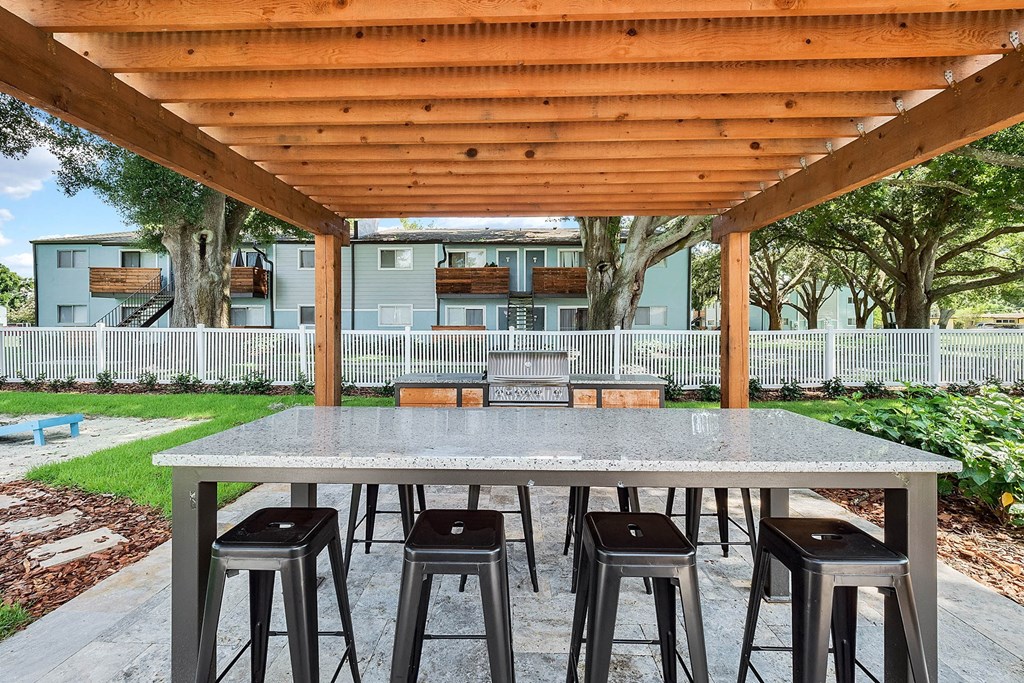 A wooden pergola over a table with four stools.
