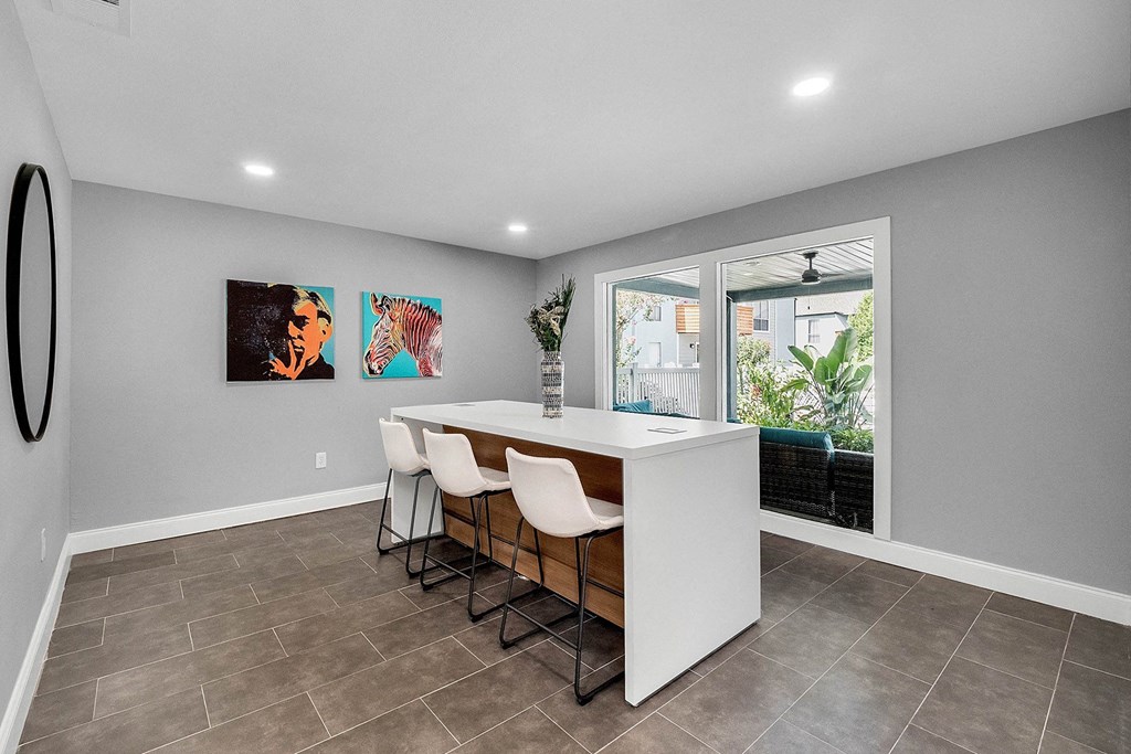 A modern kitchen with a bar area and a painting of a man and a zebra on the wall.