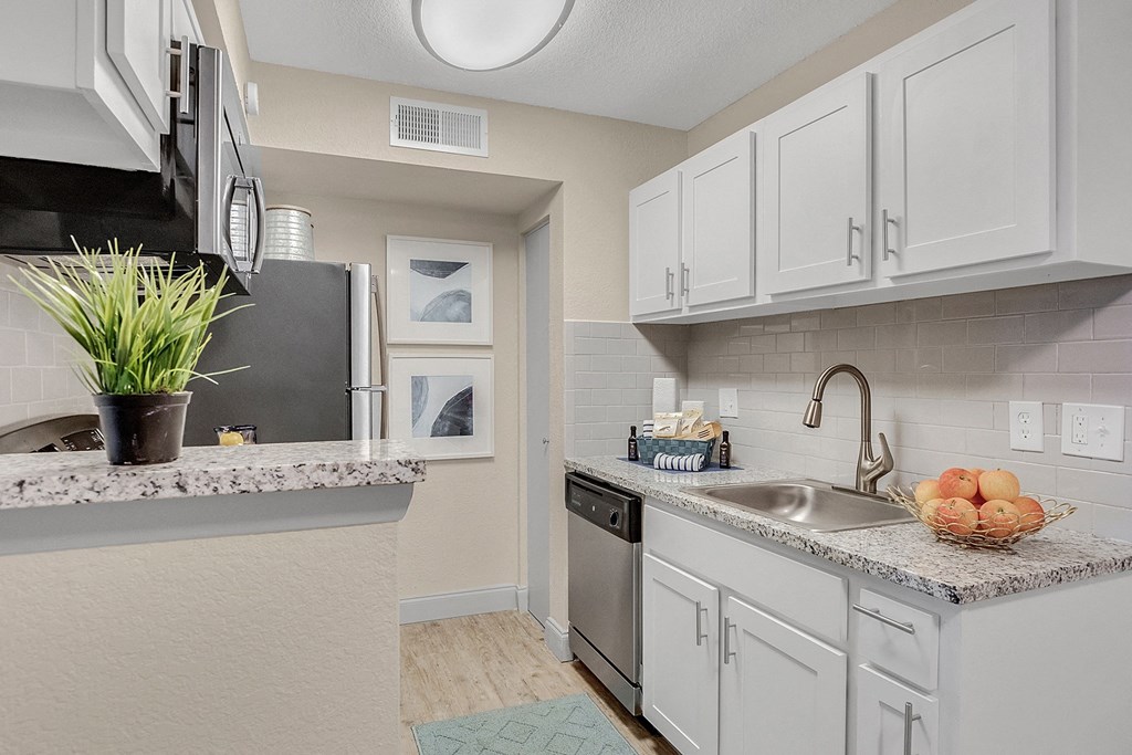 A kitchen with white cabinets and a granite countertop.