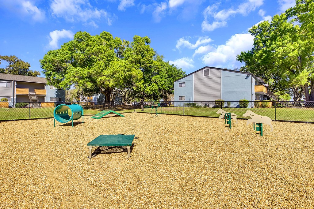 A playground with a green slide, a green table and a white dog statue.