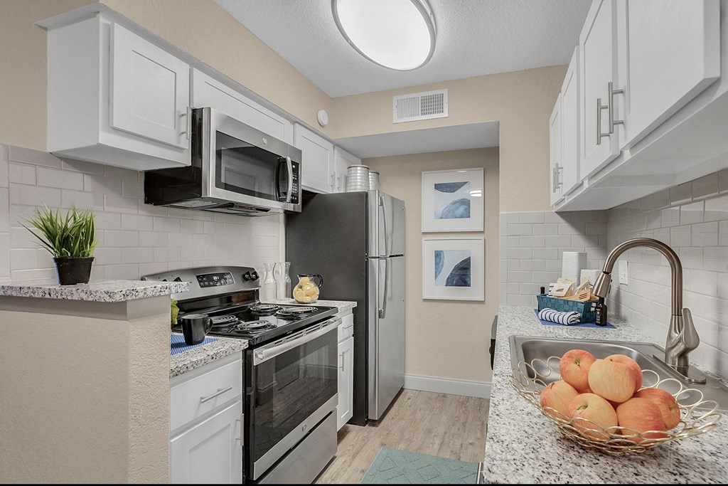 A kitchen with a black refrigerator and white cabinets.