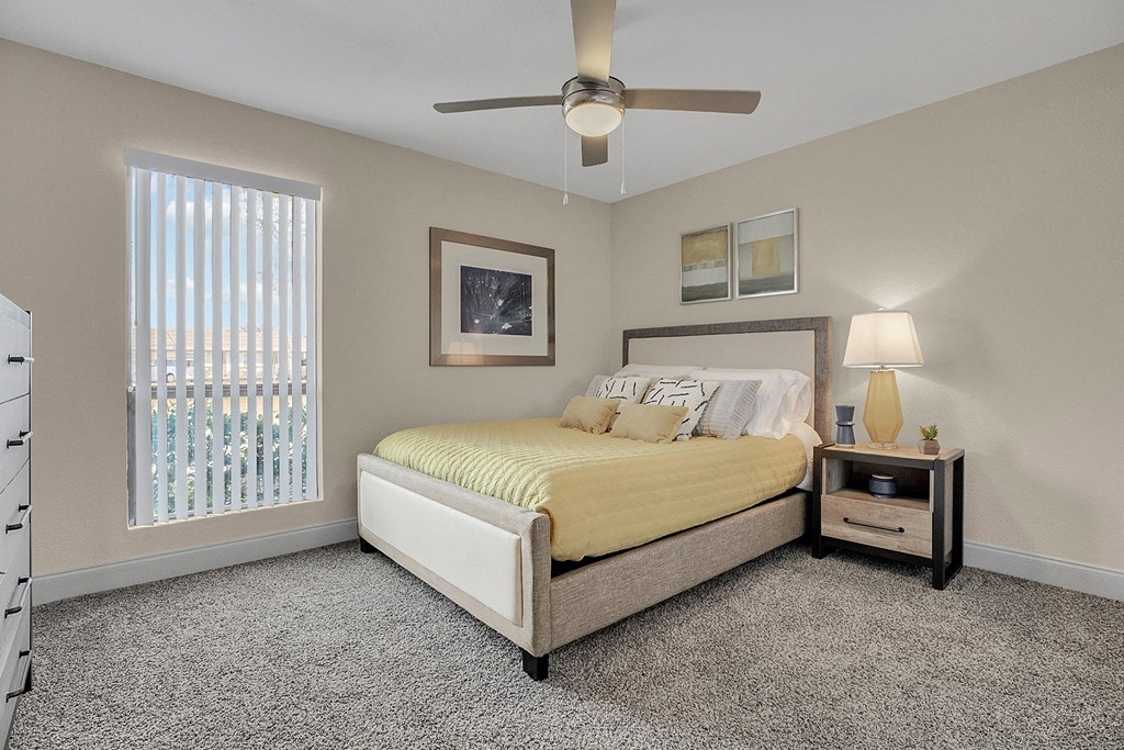A bedroom with a bed, nightstand, and a ceiling fan.