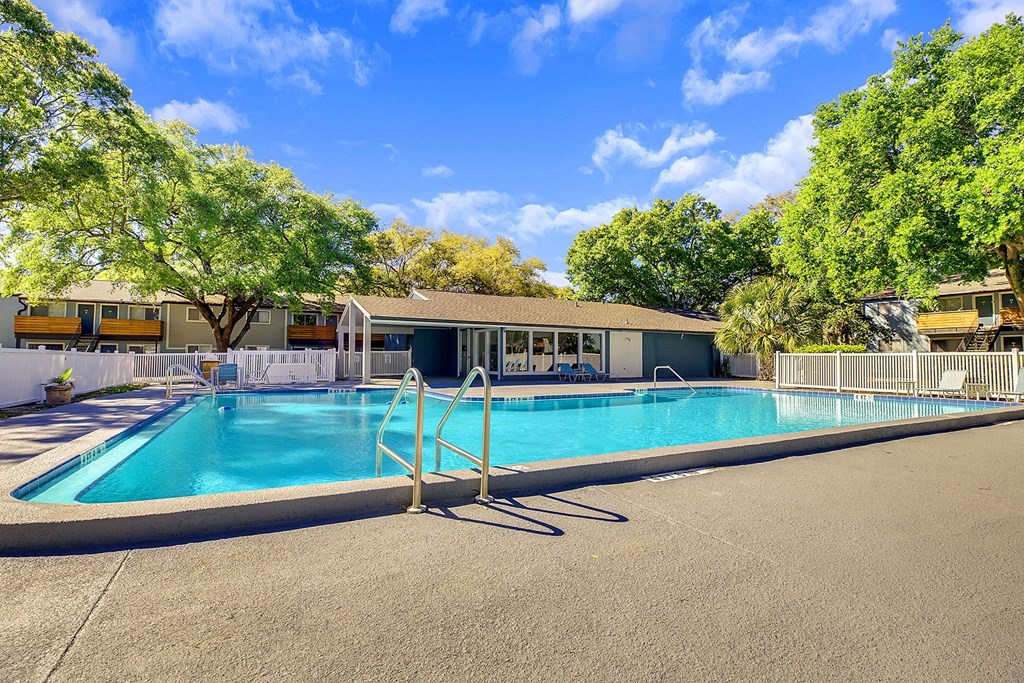 A swimming pool surrounded by trees and a building in the background.