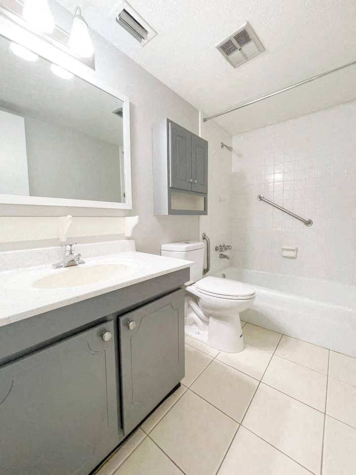 A white toilet sits in a bathroom next to a sink.