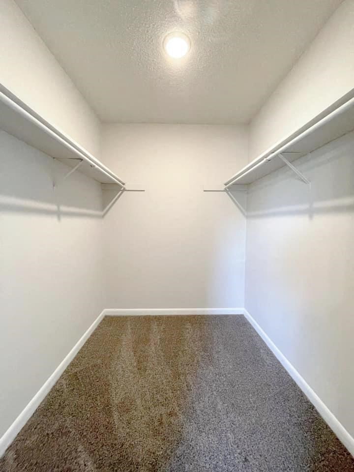 A long, narrow hallway with a carpeted floor and white walls.