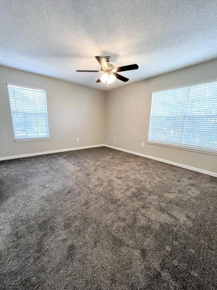 A room with a ceiling fan and carpeted floor.