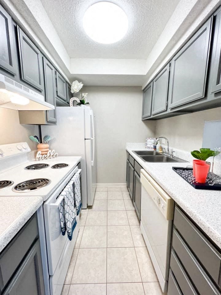 A kitchen with a white stove top oven and a white refrigerator.
