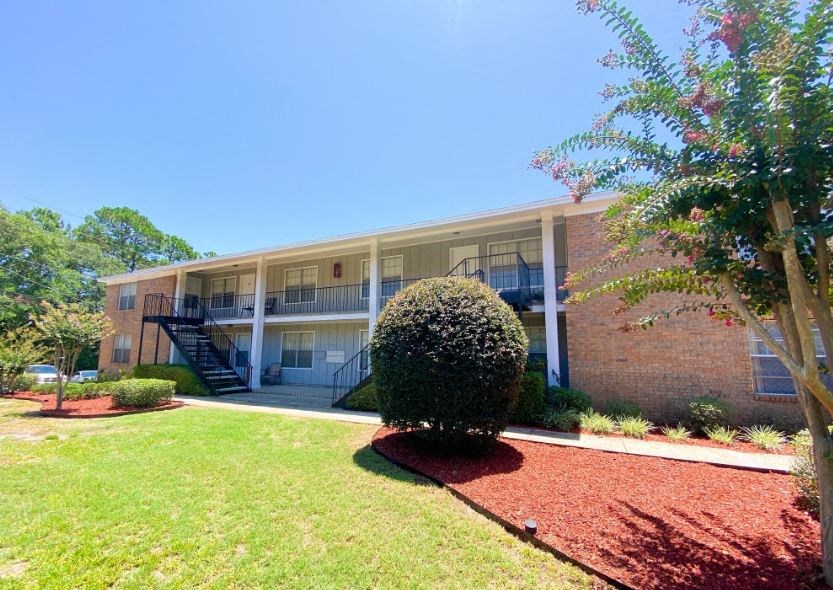 A building with a red brick wall and a green lawn in front.
