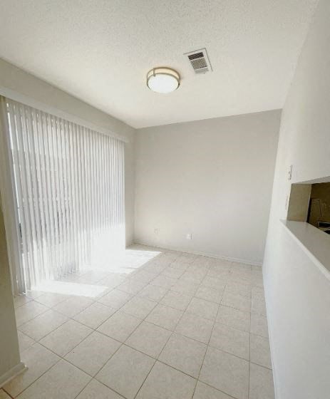 A white tiled room with a window covered in blinds.