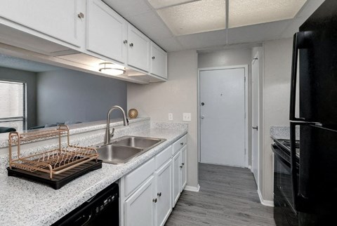 A kitchen with white cabinets and a black refrigerator.