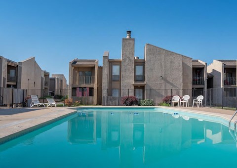A swimming pool in front of a building with a clear blue sky.