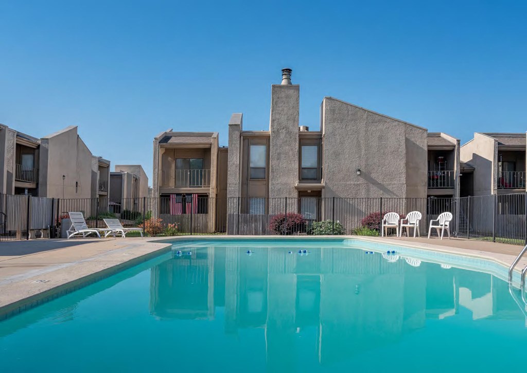 A swimming pool in front of a building with a clear blue sky.