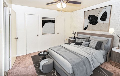 A bedroom with a bed, a ceiling fan, and a painting on the wall.