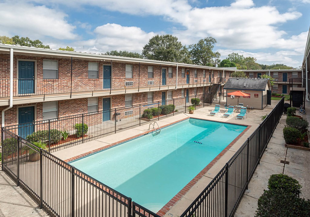 A swimming pool in a courtyard surrounded by a black fence.