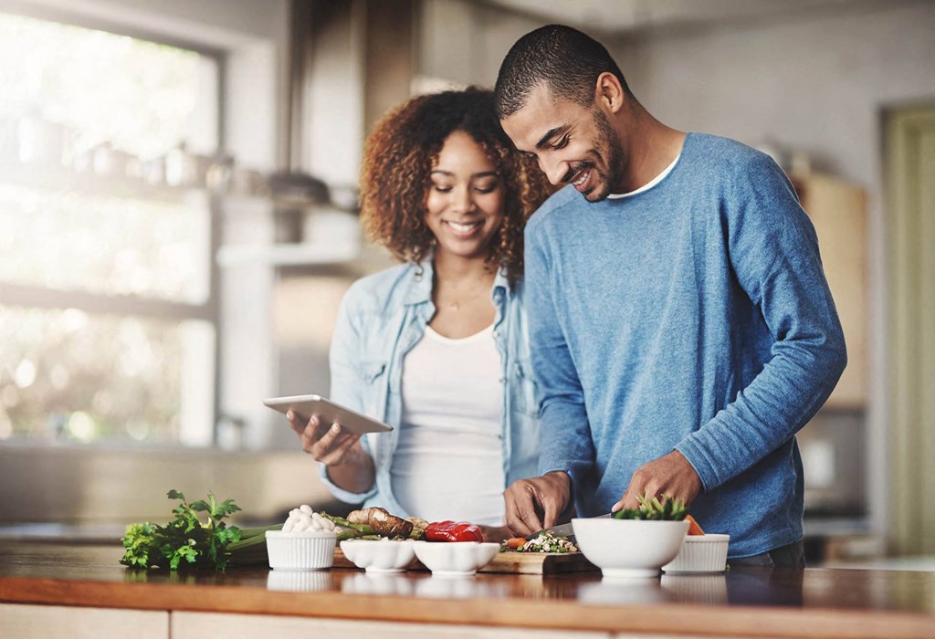 A couple is preparing a meal together in a well-lit kitchen.