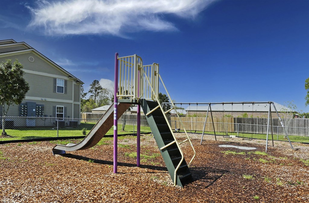 A playground with a green slide and a purple railing.