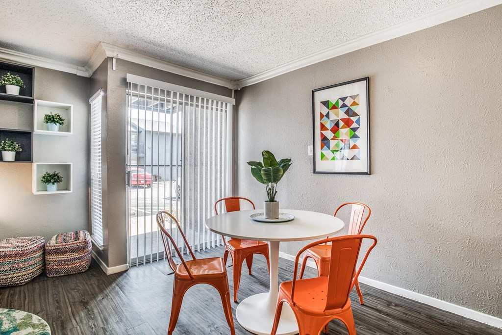 A dining room with a white table and orange chairs.