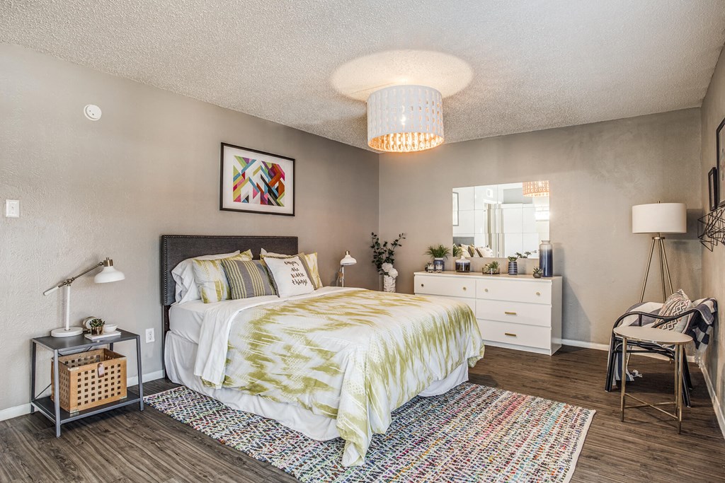 A bedroom with a bed, nightstand, and chair.