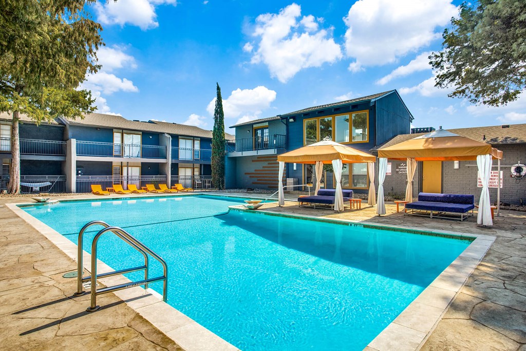 A swimming pool surrounded by a stone border and a metal ladder.