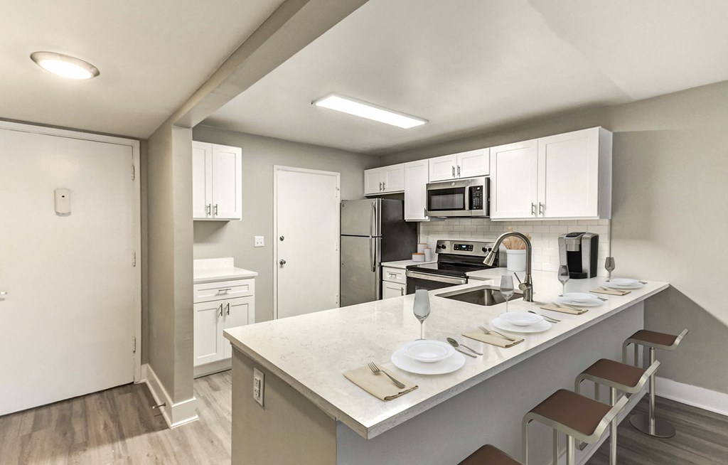 A kitchen with a white counter top and brown bar stools.
