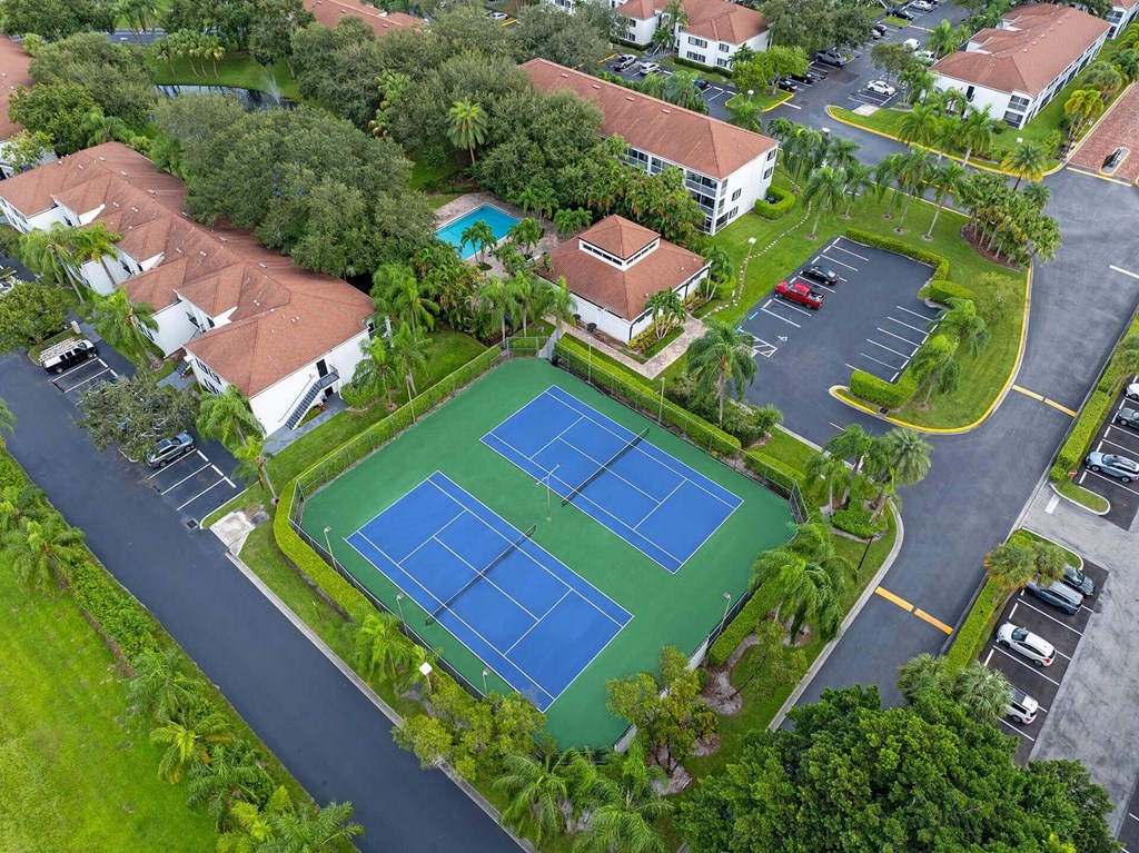 A tennis court surrounded by houses and trees.