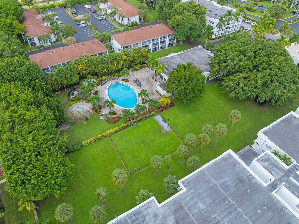 An aerial view of a resort with a swimming pool surrounded by trees.