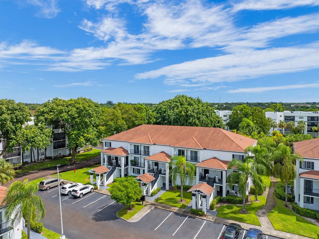 A parking lot with cars and a building with a red roof.