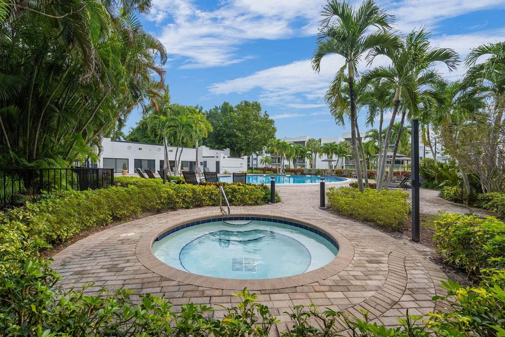 A round pool surrounded by a brick border with a white building in the background.