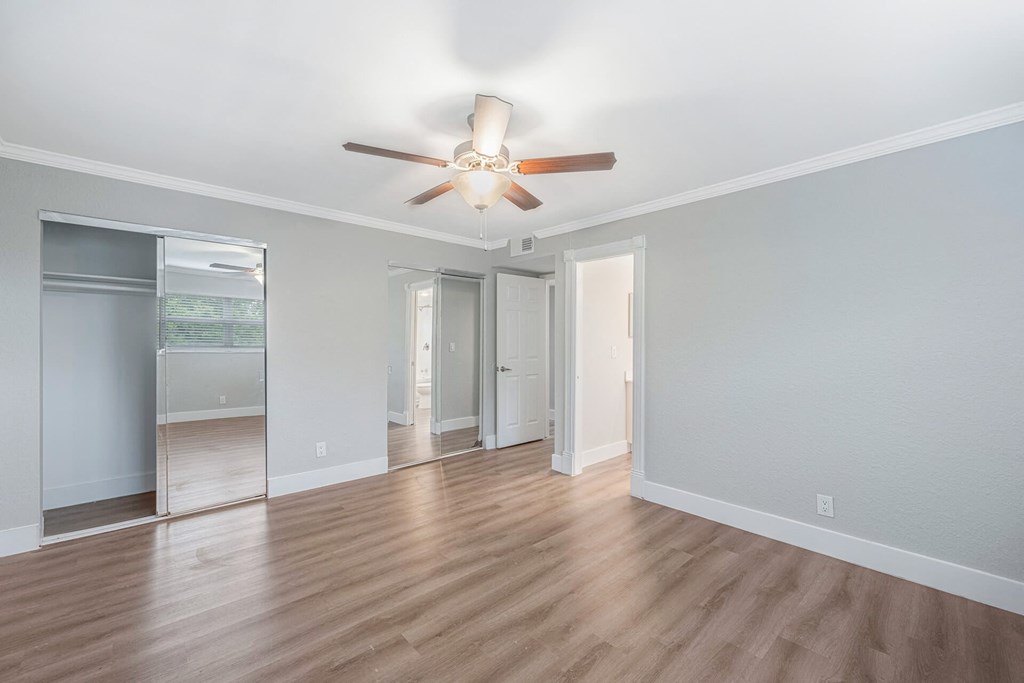 A room with a ceiling fan and wooden flooring.