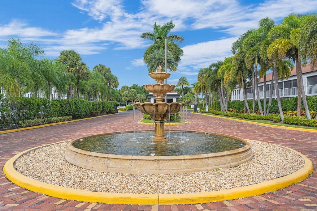 A fountain in the middle of a circular brick walkway.