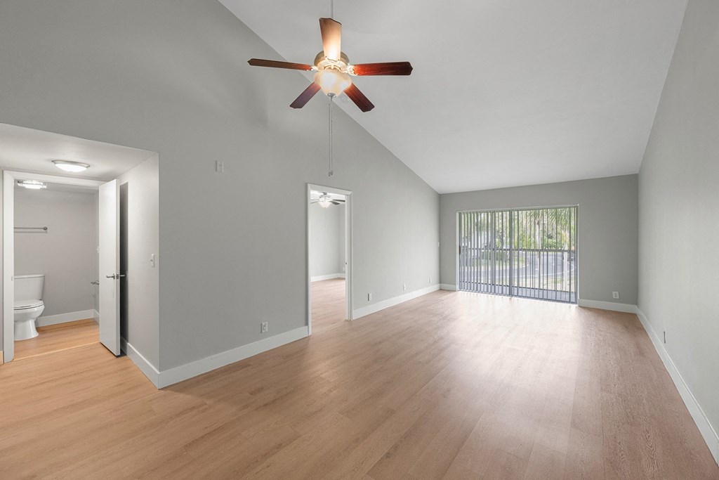 A room with a ceiling fan and wooden flooring.