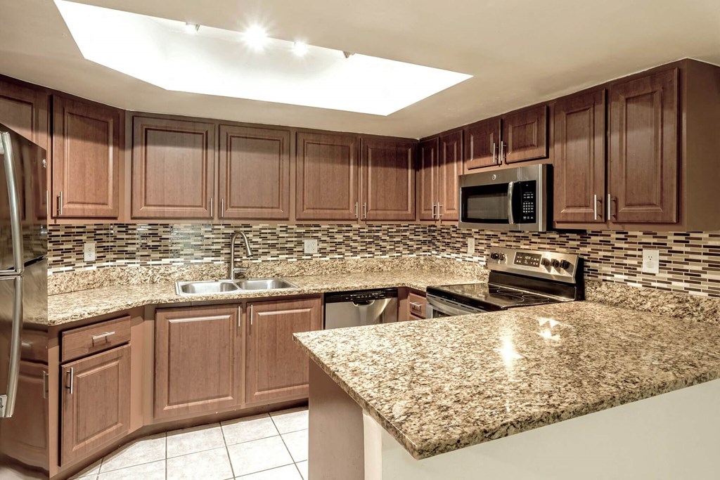 A kitchen with brown cabinets and granite countertops.