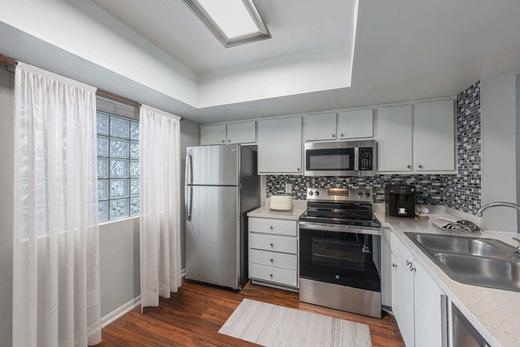 A kitchen with white cabinets and a stainless steel refrigerator.