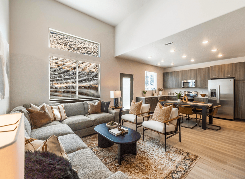 A modern living room with a grey sofa, a coffee table, and a kitchen in the background.