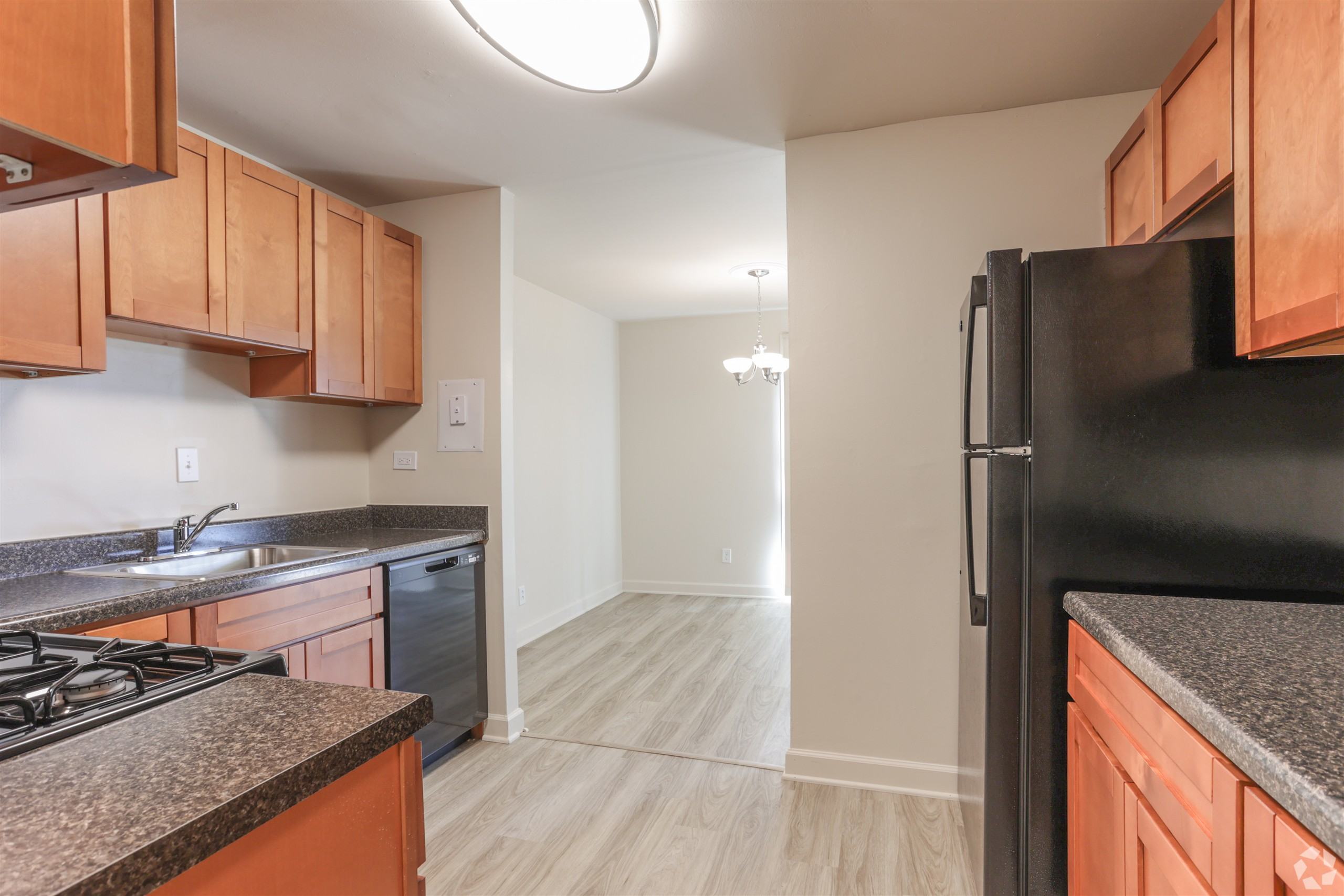 A kitchen with wooden cabinets and a black refrigerator.