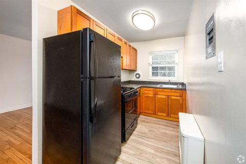 A black refrigerator in a kitchen with wooden cabinets.