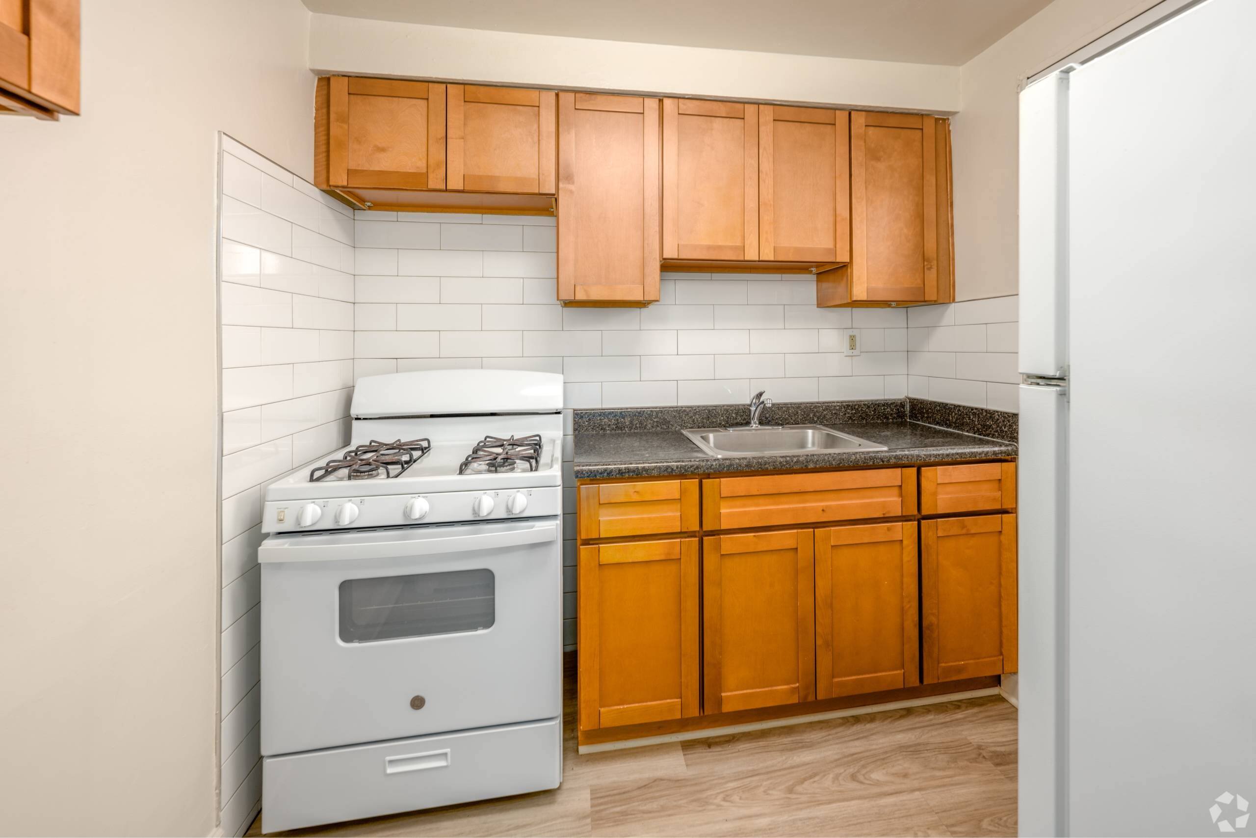 A kitchen with a stove, sink, and cabinets.