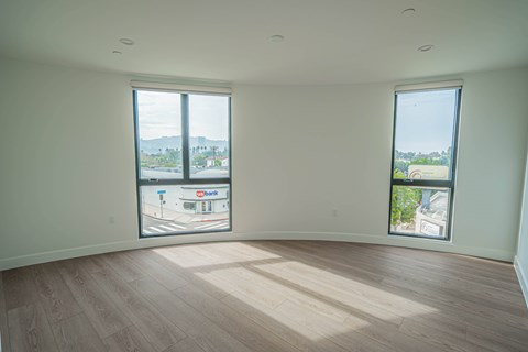 A large empty room with wooden floors and two windows.
