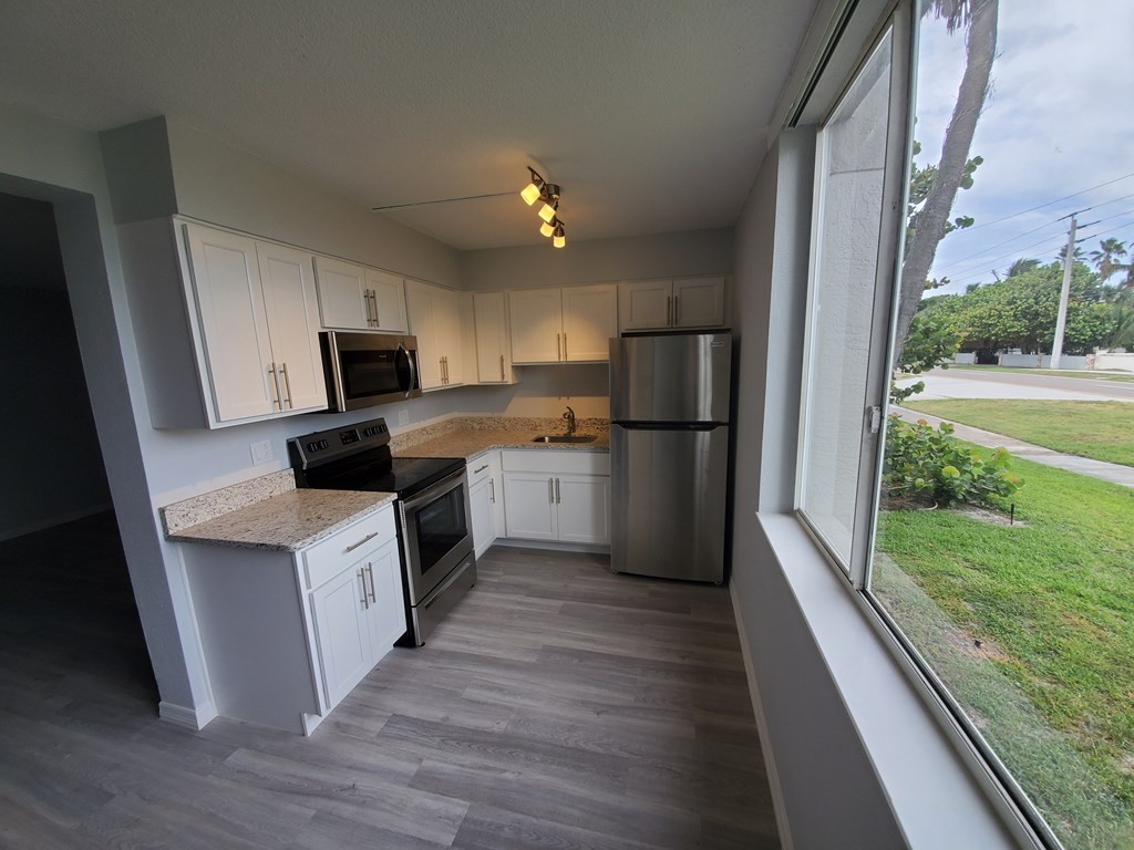 A kitchen with white cabinets and a marble countertop.