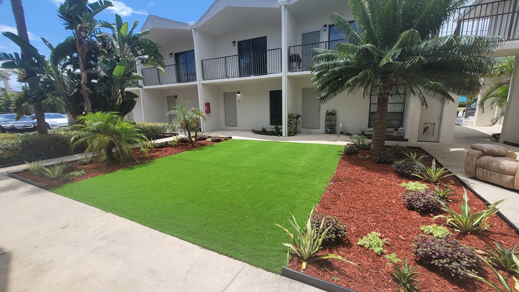 A white building with a green lawn in front.