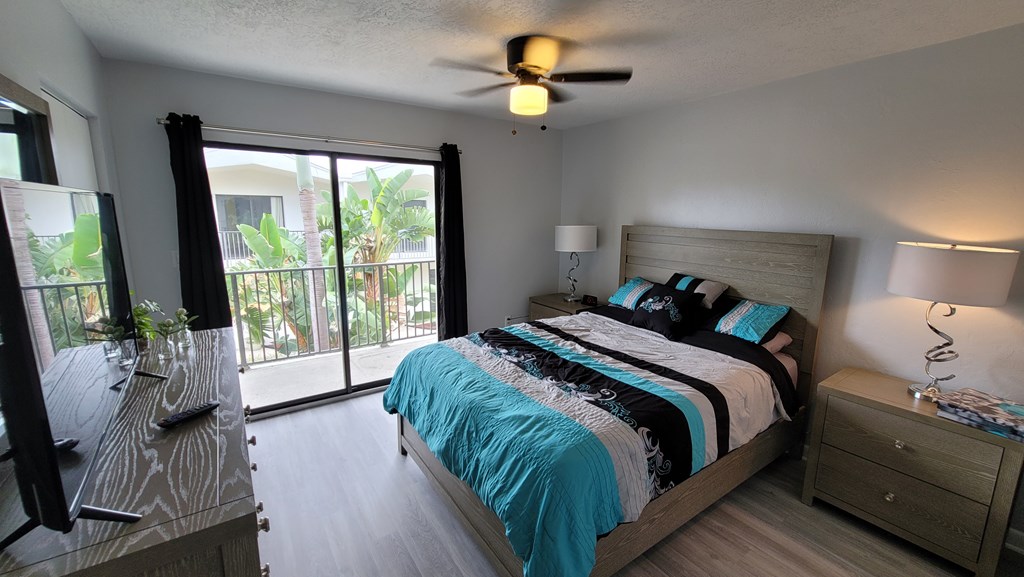 A bedroom with a bed, dresser, and sliding glass doors.