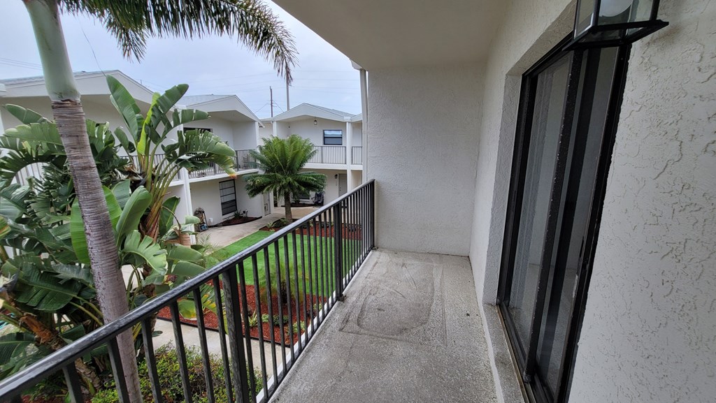 A balcony with a black railing and a view of a building and trees.