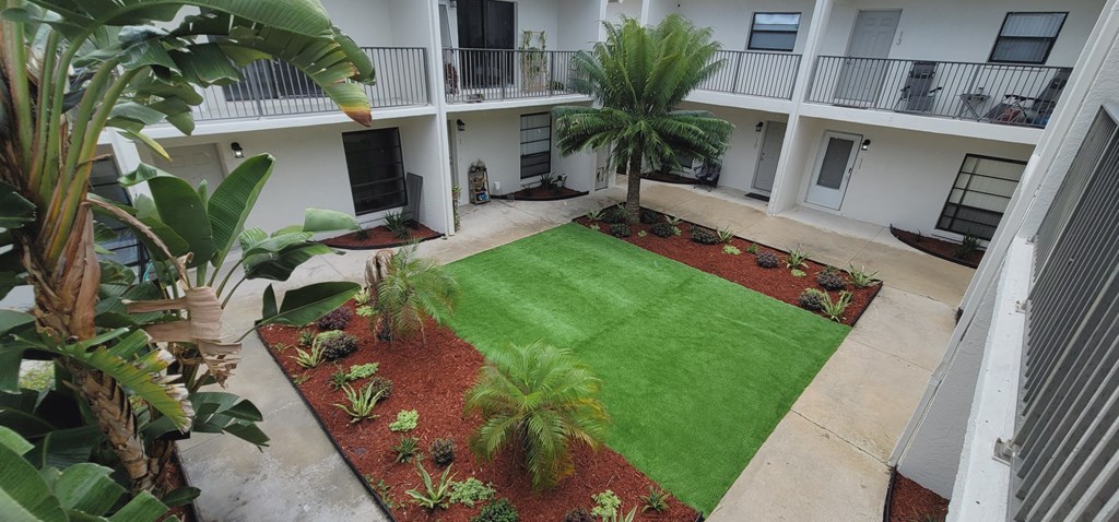 A courtyard with a green lawn and red mulch.