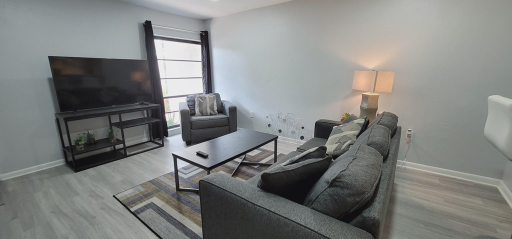 A living room with a grey couch, a black coffee table, and a flat screen TV.