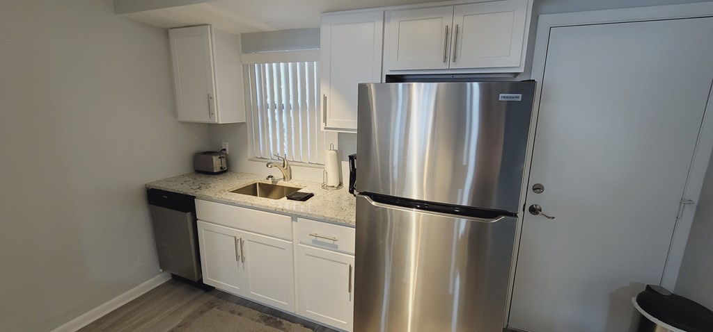 A small kitchen with a sink, toaster, and a refrigerator.