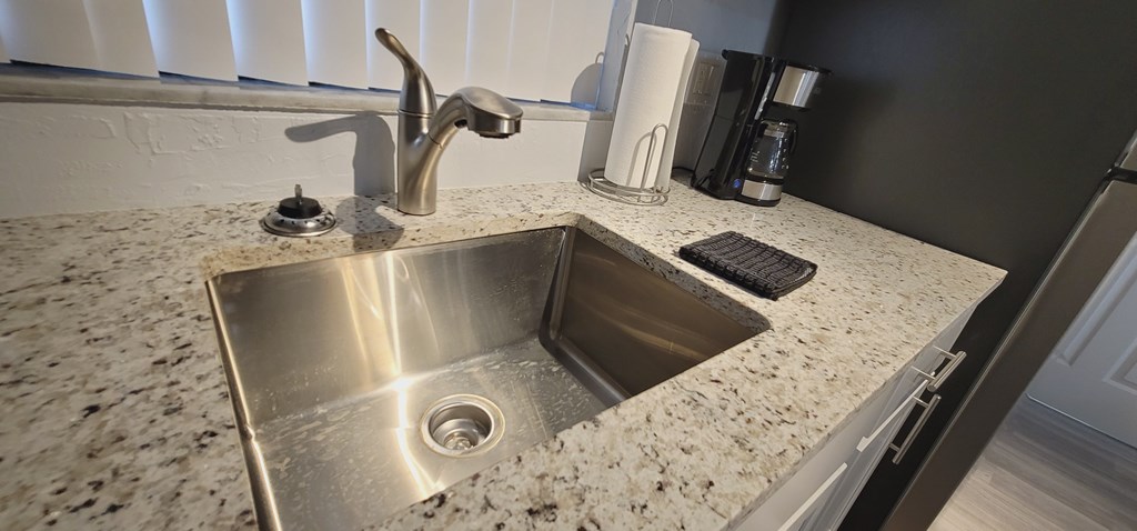 A modern kitchen with a granite countertop and a stainless steel sink.