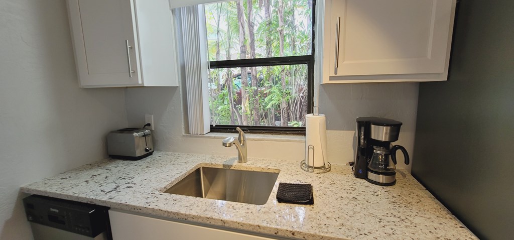 A kitchen with a sink, toaster, and coffee maker.