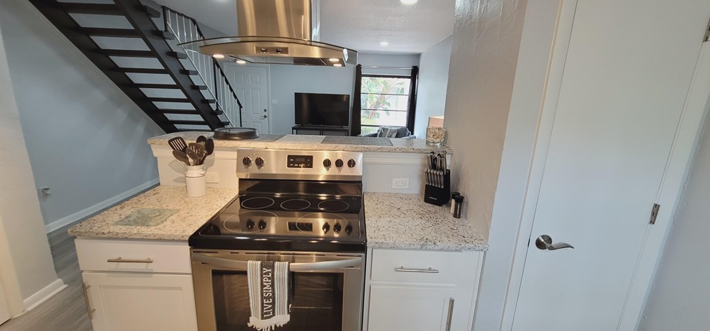 A kitchen with a stove top oven and a stainless steel range hood.