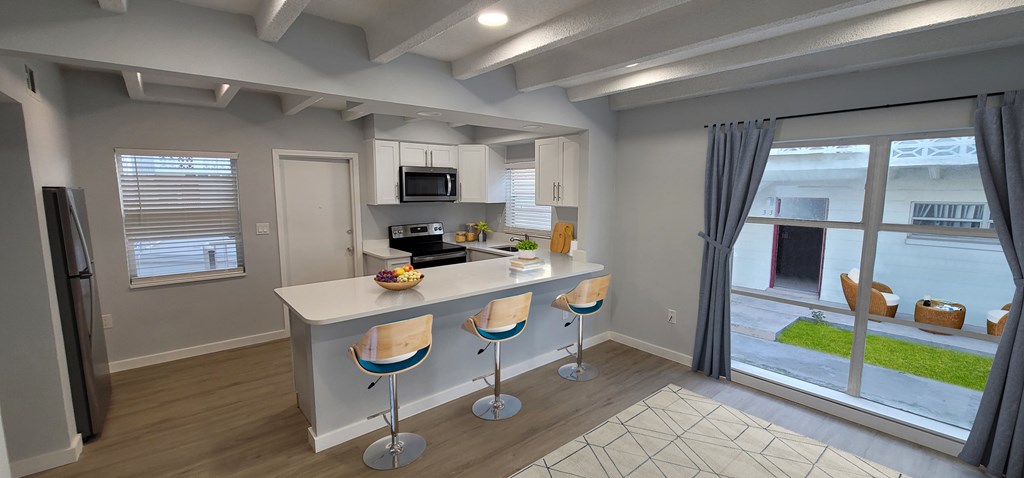 A kitchen with a bar stool and a fridge.