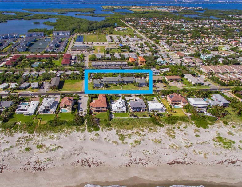 A bird's eye view of a beachfront community with a blue rectangle highlighting a specific property.
